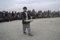 A boy sales eggs to spectators during wrestling matches in Kabul, Afghanistan, Friday, Dec. 3 , 2021. The scene is one played out each week after Friday prayers in the sprawling Chaman-e-Huzori park in downtown Kabul, where men, mainly from Afghanistan's northern provinces, gather to watch and to compete in pahlawani, a traditional form of wrestling. (AP Photo/ Petros Giannakouris)