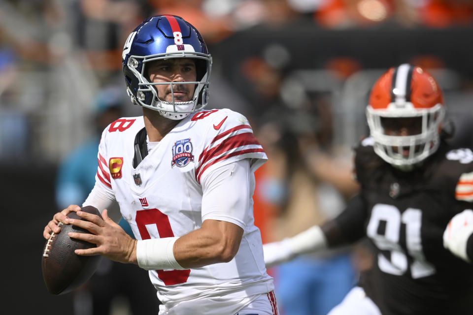 New York Giants quarterback Daniel Jones, left, looks to pass as Cleveland Browns defensive end Alex Wright (91) applies pressure during the first half of an NFL football game, Sunday, Sept. 22, 2024 in Cleveland. (AP Photo/David Richard)