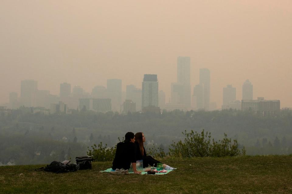 Smoke from wildfires blankets the city as a couple has a picnic in Edmonton, Alberta on May 11, 2024 (AP)
