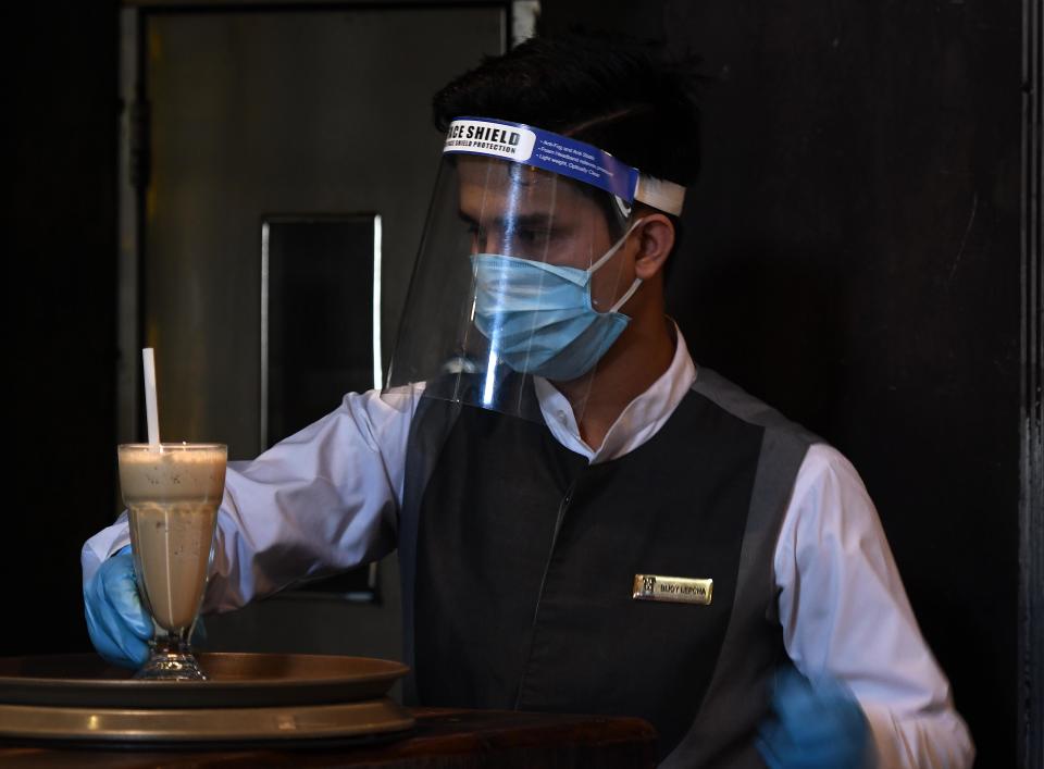 NEW DELHI, INDIA - JUNE 9: A waiter wearing a face mask, gloves and shield at Town Hall restaurant as lockdown restrictions ease at Khan Market on June 9, 2020 in New Delhi, India. (Photo by Biplov Bhuyan/Hindustan Times via Getty Images)