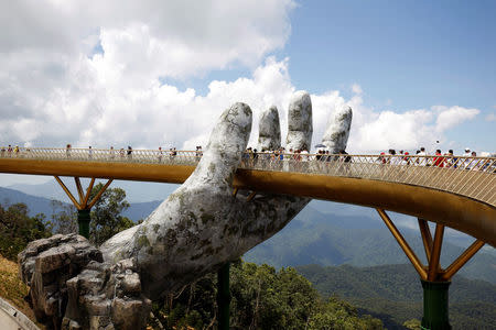 Tourists walk past giant hand structure on Gold Bridge on Ba Na hill near Danang city, Vietnam August 1, 2018. REUTERS/Kham