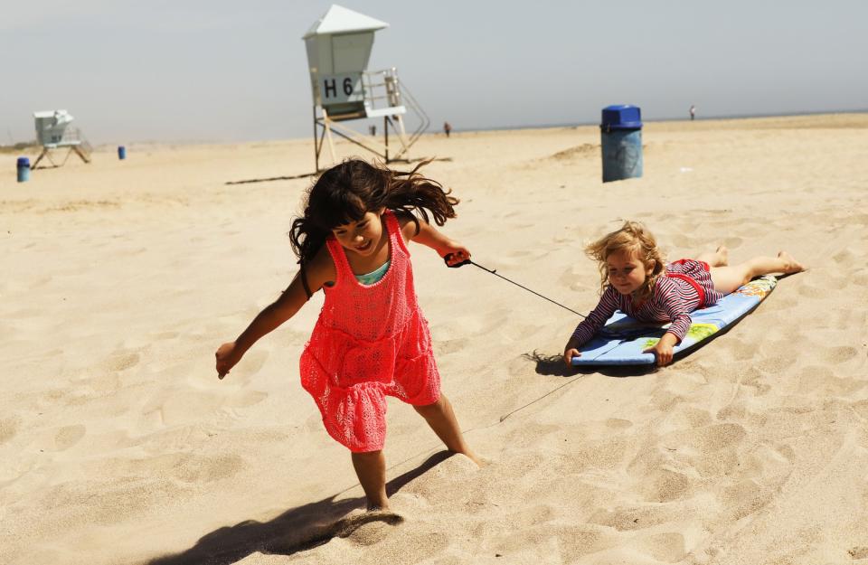 Emily Enholm, 7, and her sister, Hazel, 4, play on the sand at Hueneme Beach. Ventura agreed to allow people to use the city's beaches, pier, promenade and parks as long as they keep their distance from one another and remain on the move.