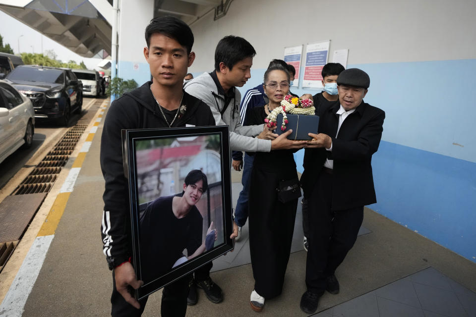 Former soccer coach Ekkapol Chanthawong, right, holds a portrait of Duangphet Phromthep as Kamaery Promthep, Duangphet's grandmother, holds his ashes at Mae Fah Luang airport in Chiang Rai province Thailand, Saturday, March 4, 2023. The cremated ashes of Duangphet, one of the 12 boys rescued from a flooded cave in 2018, arrived in the far northern Thai province of Chiang Rai on Saturday where final Buddhist rites for his funeral will be held over the next few days following his death in the U.K. (AP Photo/Sakchai Lalit)