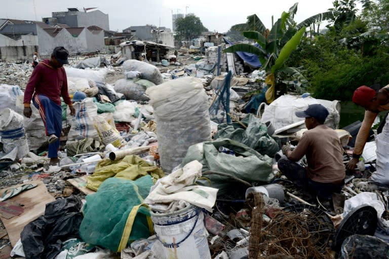 Indonesian workers pack the recyclable items collected by scavengers at a dumpsite in Jakarta