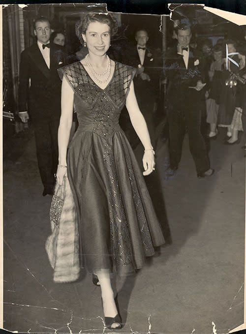 After seeing a performance of 'The Boyfriend' in 1954, Her Majesty was photographed walking out of the Wyndham Theatre wearing sparkling blue lace dress, carrying a jewelled handbag and carrying a fur stole.