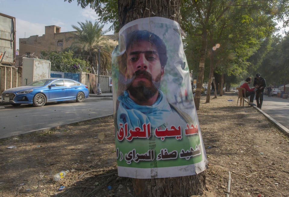 A poster with a picture of an anti-government protester who was killed in demonstrations, and Arabic that reads, "no one loves Iraq like he did, the Martyr Safa al-Sarai," hangs on a tree near Tahrir square, in Baghdad, Iraq, Wednesday, Dec. 25, 2019. (AP Photo/Nasser Nasser)