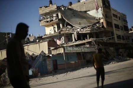 Palestinians stand next to a house which police said was targeted in an Israeli air strike in Gaza City July 17, 2014. REUTERS/Mohammed Salem