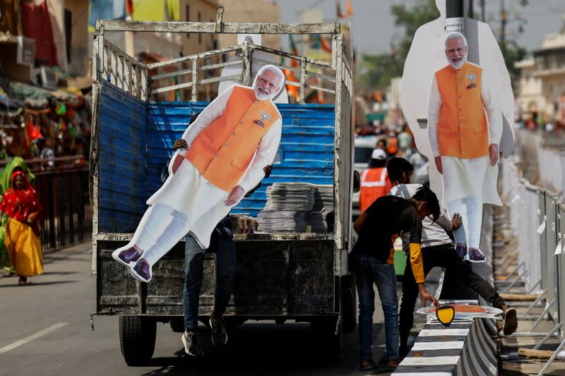 FILE PHOTO: A person carries a cutout of India’s Prime Minister Modi, ahead of his election campaign rally, in Ayodhya