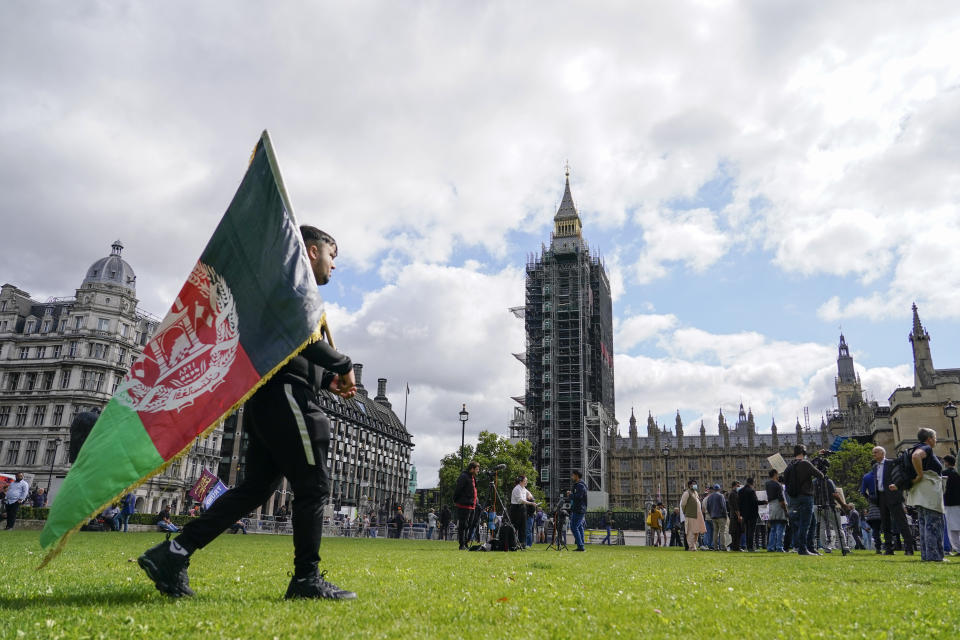 A demonstrator walks holding an Afghanistan flag, during a protest at Parliament Square in London, Wednesday, Aug. 18, 2021. British Prime Minister Boris Johnson is set to update lawmakers Wednesday about the evacuation of British nationals and local allies from Afghanistan. Big Ben's clock tower shrouded in scaffolding at centre. (AP Photo / Alberto Pezzali)