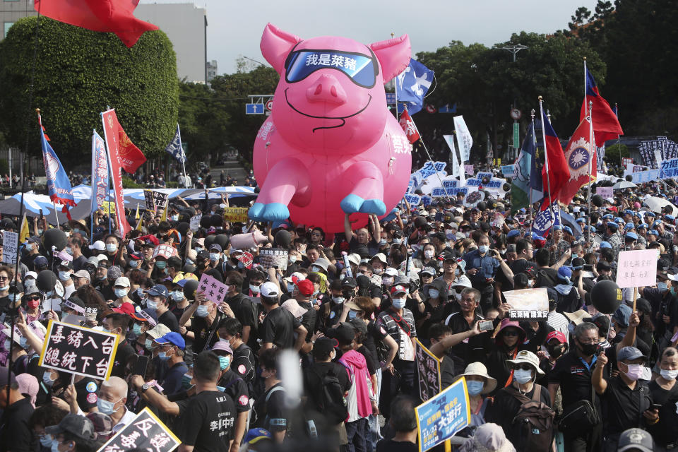 People hold a pig model with "I am a ractopamine pig" written on it during a protest in Taipei, Taiwan, Sunday, Nov. 22. 2020. Thousands of people marched in streets on Sunday demanding the reversal of a decision to allow U.S. pork imports into Taiwan, alleging food safety issues. (AP Photo/Chiang Ying-ying)