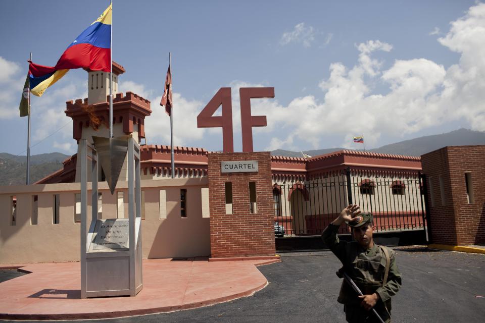 Un soldado hace guardia en un antiguo cuartel militar donde el difunto Hugo Chávez comandó un fallido golpe de Estado en 1992, y que se ha convertido en el mausoleo de Chávez. La foto fue tomada en Caracas, Venezuela, el martes 4 de marzo de 2014. En su interior reposa una tumba de mármol flanqueada por soldados que llevaban el uniforme de estilo húsar que era usado por el héroe de la independencia Simón Bolívar. El uniforme incluye una chaqueta apretada adornada con galones dorados y un sombrero negro, alto, con correa a la barbilla. (AP Foto/ Rodrigo Abd).