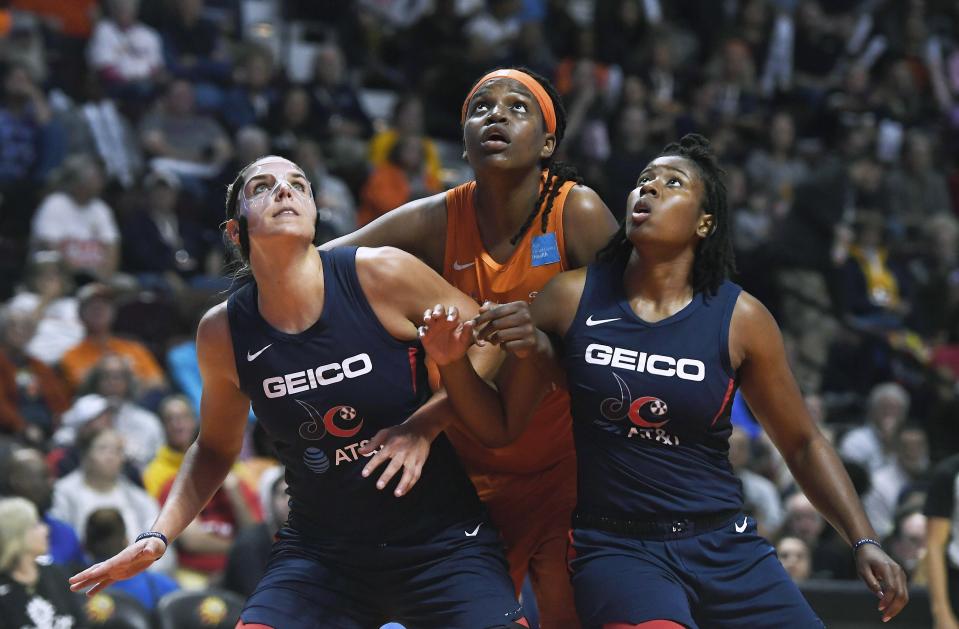 Connecticut Sun's Jonquel Jones, center, fights for position under the basket between Washington Mystics' Elena Delle Donne, left, and Ariel Atkins, ritht, during the first half in Game 4 of basketball's WNBA Finals, Tuesday, Oct. 8, 2019, in Uncasville, Conn. (AP Photo/Jessica Hill)