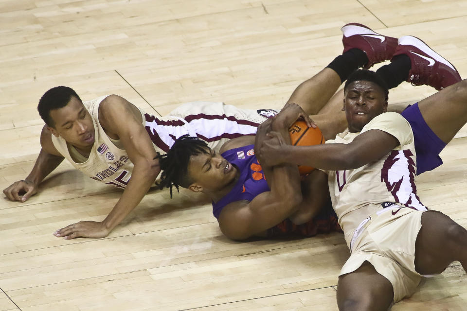 Clemson forward RJ Godfrey, center, and Florida State guard Chandler Jackson fight for control of the ball as Florida State guard Matthew Cleveland, left, looks on in the first half of an NCAA college basketball game in Tallahassee, Fla., Saturday, Jan. 28, 2023. (AP Photo/Phil Sears)