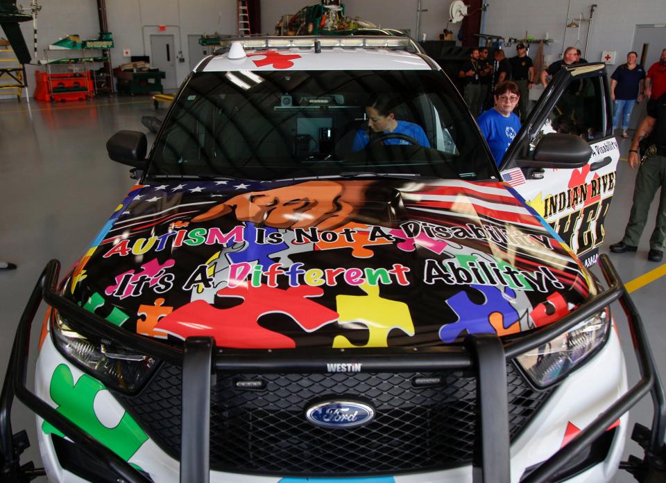 Sheriff Eric Flowers, along with sponsors and local representatives gather at the Indian River County Sheriff's Office hangar, Wednesday, July 26, 2023, to unveil their autism awareness vehicle.