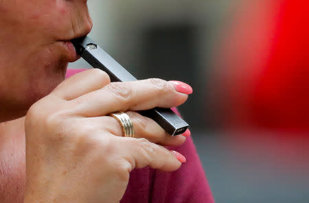 FILE PHOTO: A woman smokes a Juul e-cigarette in New York, U.S., September 27, 2018. REUTERS/Brendan McDermid/File Photo