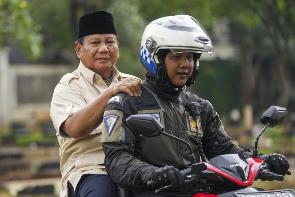 Indonesian Defense Minister and presidential frontrunner Prabowo Subianto rides on the back of a motorbike driven by a police officer during a visit to his father's grave in Jakarta, Indonesia Thursday, Feb. 15, 2024. The wealthy ex-general looks set to be the country's next president after unofficial tallies showed him taking a clear majority in the first round of voting. (AP Photo/Tatan Syuflana)