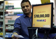 <p>Screen display the lottery prizes, as store clark Malik Imran serves customer, Aug. 22, 2017, in Chicago. Officials estimated jackpot for Wednesday night’s Powerball lottery game has climbed to $700 million, making it the second largest in U.S. history. (Photo: G-Jun Yam/AP) </p>