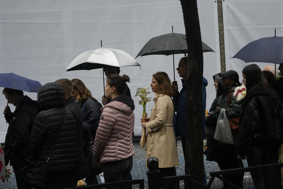 People gather in front of the Vladislav Ribnikar school during a memorial ceremony to mark the first anniversary of a shooting that killed 10 people in Belgrade, Serbia, Friday, May 3, 2024. (AP Photo/Darko Vojinovic)
