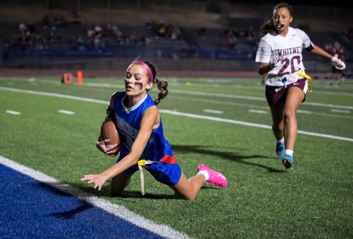 Rocklin Thunder Elise Mullican (4) makes a touchdown catch off a pass to the rear of the high school girls flag football end zone by quarterback Robyn Nguyen, as Whitney Wildcats Alex Salazar (20) covers at right, to bring the score to 18-0 near the end of the game Thursday, Sept. 28, 2023, at Rocklin High School. During the inaugural “Battle for the Belt” showdown, the school took aim at its previous record for attendance at a girls sporting event. Xavier Mascareñas/xmascarenas@sacbee.com