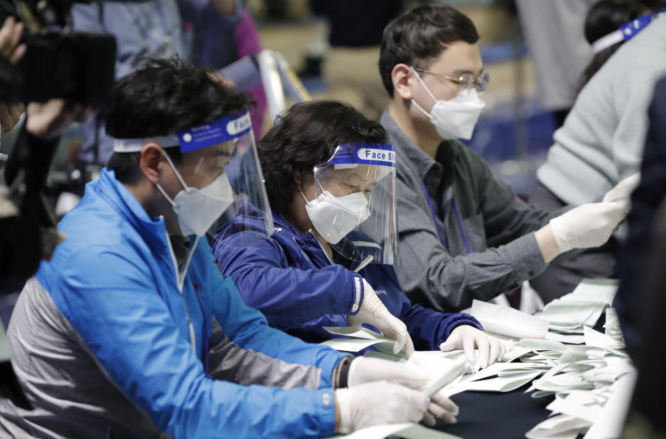 South Korean National Election Commission officials wearing masks and face shields, sort out ballots for counting at the parliamentary election at a ballot counting office in Seoul, South Korea, Wednesday, April 15, 2020. South Korean voters wore masks and moved slowly between lines of tape at polling stations on Wednesday to elect lawmakers in the shadows of the spreading coronavirus. (AP Photo/Lee Jin-man)