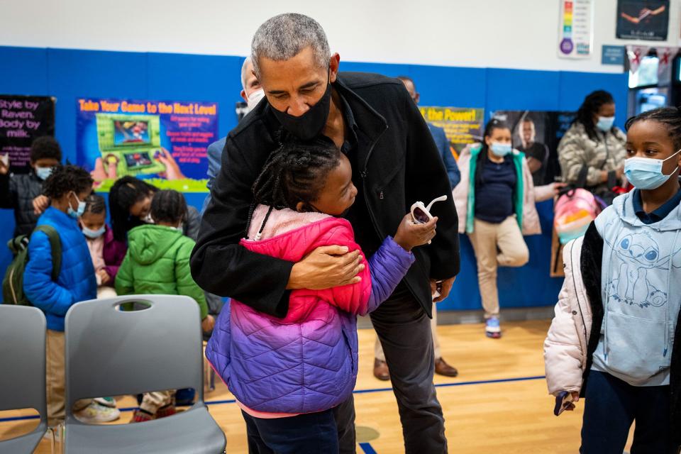 WASHINGTON, DC - NOVEMBER 30: Former U.S. President Barack Obama hugs a student while talking with elementary school students as they prepare to get their second vaccine shots at the Kimball Elementary School on November 30, 2021 in Washington, DC. (Photo by Doug Mills-Pool/Getty Images)