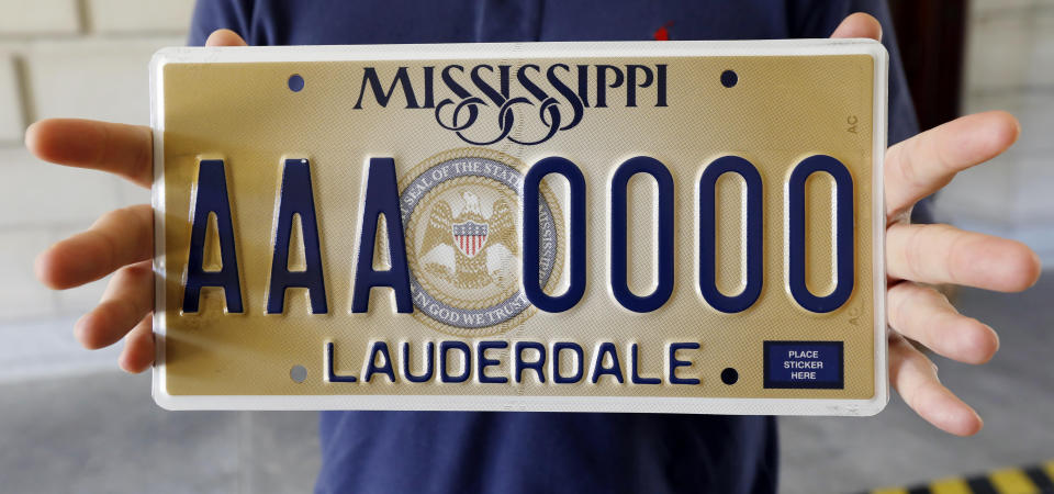 FILE - In a May 10, 2018 file photograph, Clay Chandler, director of communications for then Gov. Phil Bryant, holds Mississippi's new standard license plate at the Capitol in Jackson, Miss. It displayed the state seal that includes the phrase, "In God We Trust." American Atheists, the Mississippi Humanist Association and three nonreligious state residents filed a lawsuit Tuesday, June 22, 2021 against the state over the slogan emblazoned license plate. (AP Photo/Rogelio V. Solis, File)