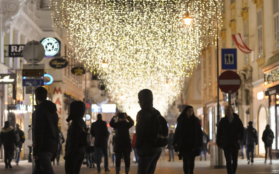 People walk on a street decorated with Christmas lights in Vienna, Austria, Saturday, Nov. 20, 2021. The Austrian government announced a nationwide lockdown that will start Monday and comes as average daily deaths have tripled in recent weeks and hospitals in heavily hit states have warned that intensive care units are reaching capacity. (AP Photo/Vadim Ghirda)