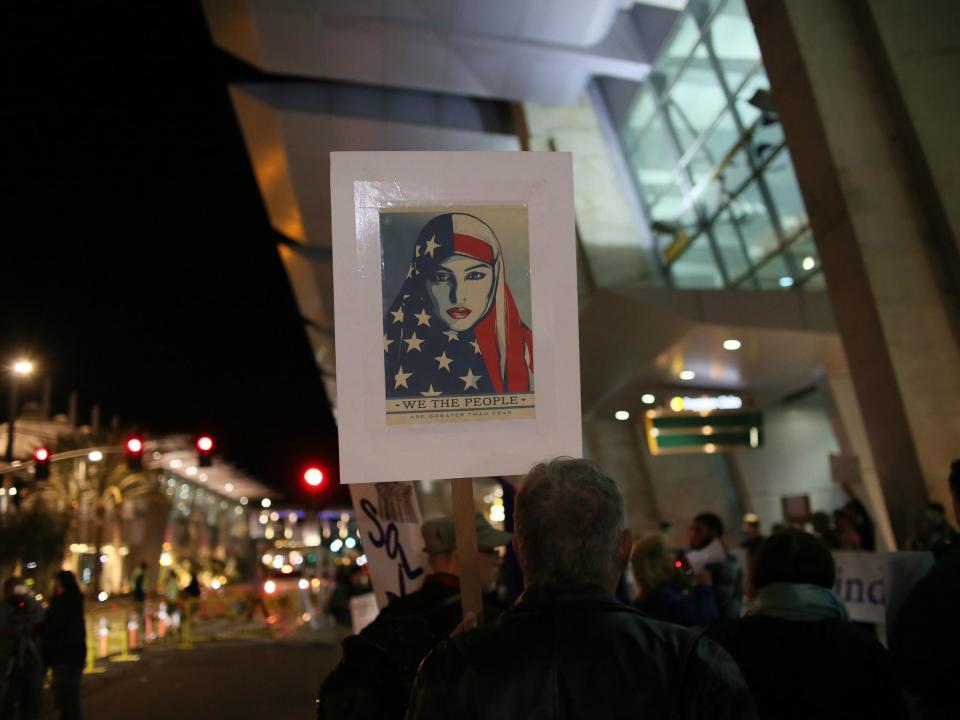 A protestor holds a sign at the airport in San Diego, California opposing Donald Trump's travel ban in January 2017: Getty