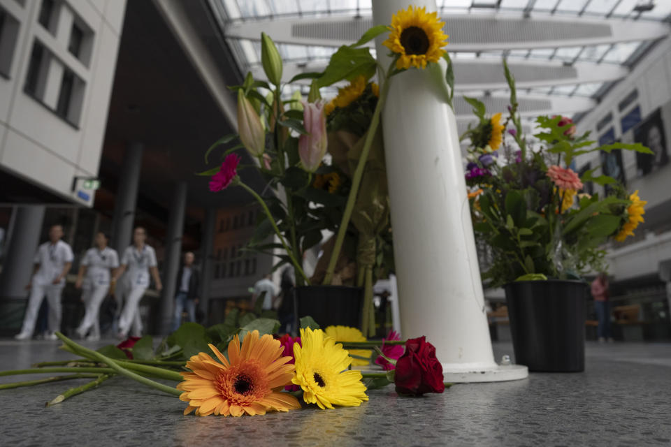 Medical personnel of the Erasmus Medical Centrum passes flowers who were left to commemorate victims of a shooting in Rotterdam, Netherlands, Friday, Sept. 29, 2023. Police in the Netherlands said a lone gunman wearing a bulletproof vest opened fire in an apartment and a hospital in the Dutch port city of Rotterdam, Thursday, Sept. 28, 2023, killing three people, including a 14-year-old girl. (AP Photo/Peter Dejong)