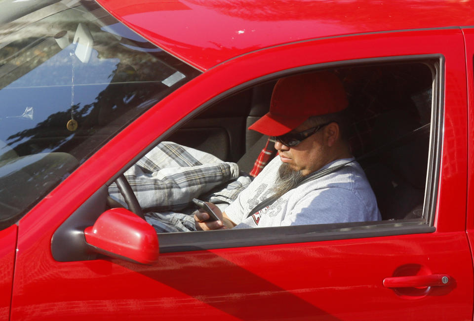 FILE - In this Dec. 14, 2011 file photo, a driver uses a cellphone while driving in Los Angeles. California regulators are considering a plan to charge a fee for text messaging on mobile phones to help support programs that make phone service accessible to the poor. The Mercury News said Wednesday, Dec. 12, 2018, the proposal is scheduled for a vote next month. (AP Photo/Damian Dovarganes, File)