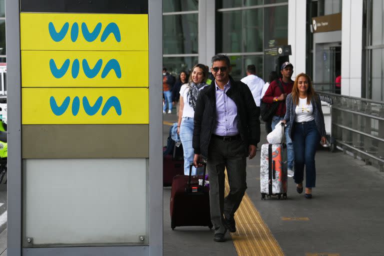 La gente pasa frente a un tablero publicitario de Viva Air afuera del aeropuerto internacional El Dorado en Bogotá el 28 de febrero de 2023