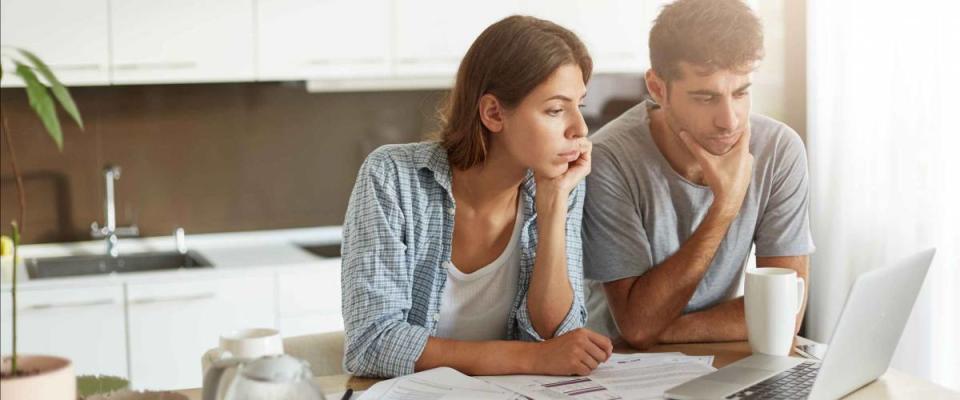 Portrait of family couple looking attentively into screen of laptop, comparing mortgage rates