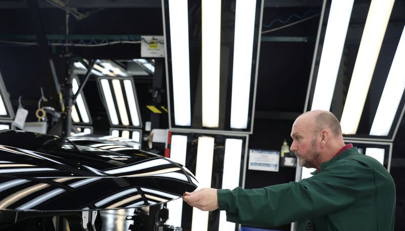 FILE PHOTO: A member of staff checks the paintwork on Range Rover bodies as they pass through the paint shop at Jaguar Land Rover’s factory in Solihull
