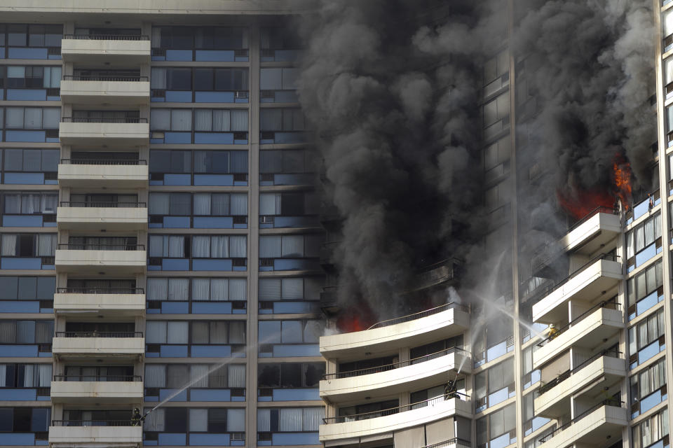 <p>Firefighters on several balconies spray water upwards while trying to contain a fire at the Marco Polo apartment complex, Friday, July 14, 2017, in Honolulu, Hawaii. (Photo: Marco Garcia/AP) </p>