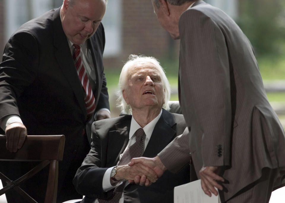CHARLOTTE, NC - MAY 31: Evangelist Billy Graham (C) is greeted by former U.S. President George H. W. Bush (R) on the stage during the Billy Graham Library Dedication Service on May 31, 2007 in Charlotte, North Carolina. Approximately 1500 guests attended the private dedication ceremony for the library, which chronicles the life and teachings of Graham. Former U.S. Presidents Bill Clinton, Jimmy Carter and George H.W. Bush made short speeches during the dedication ceremony. (Photo by Davis Turner/Getty Images)
