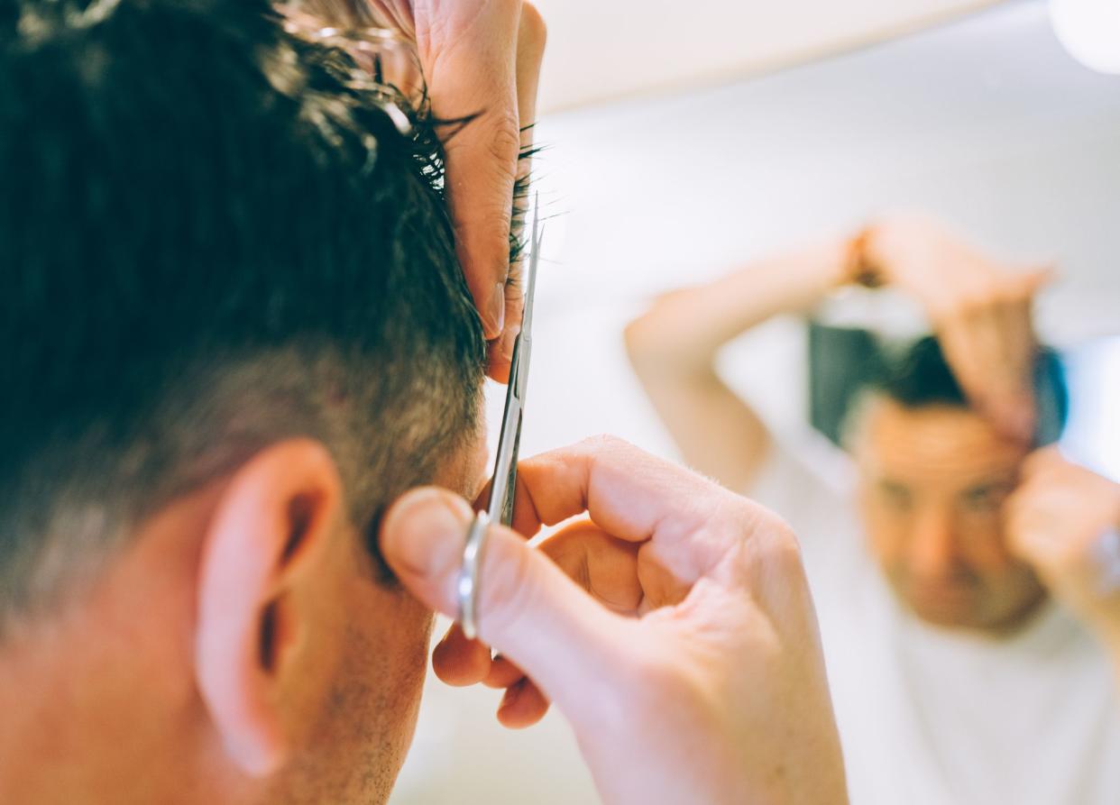 A man cutting his hair at home