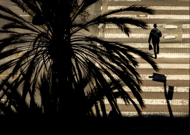 Los Angeles, CA - April 19: Afternoon sun and shadows silhouettss a pedestrian walking through a crosswalk pattern along Wilshire Blvd. amidst pleasant weather in the Koreatown area of Los Angeles Tuesday, April 19, 2022. (Allen J. Schaben / Los Angeles Times)