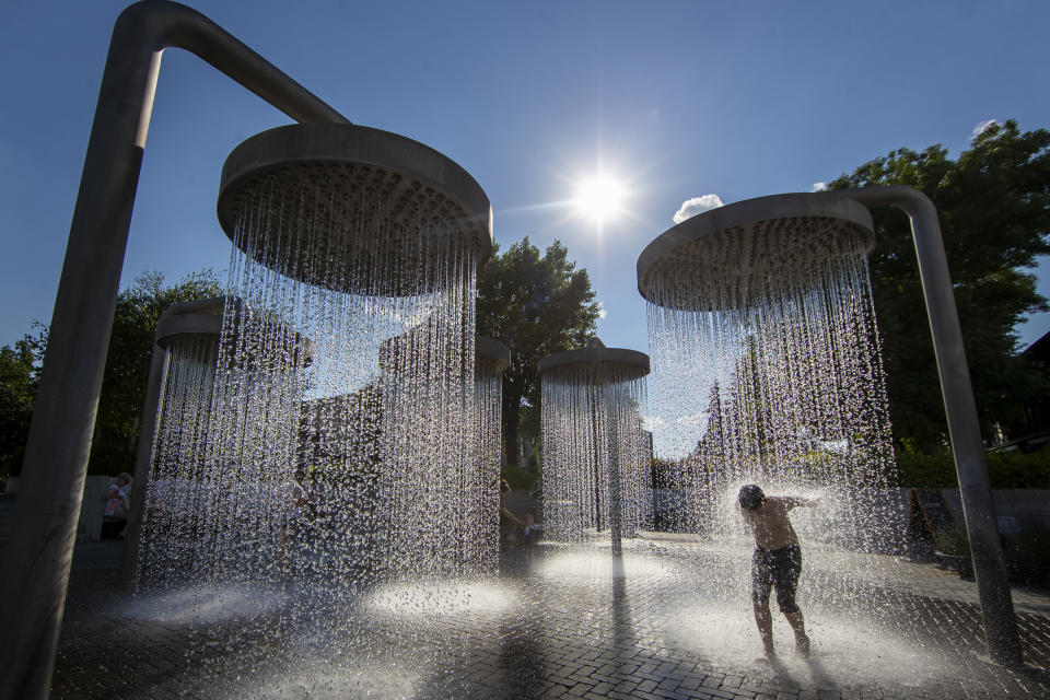 Un niño se refresca en una fuente pública en Vilna, Lituania, el 26 de junio de 2022, durante una ola de calor. (AP Foto/Mindaugas Kulbis)