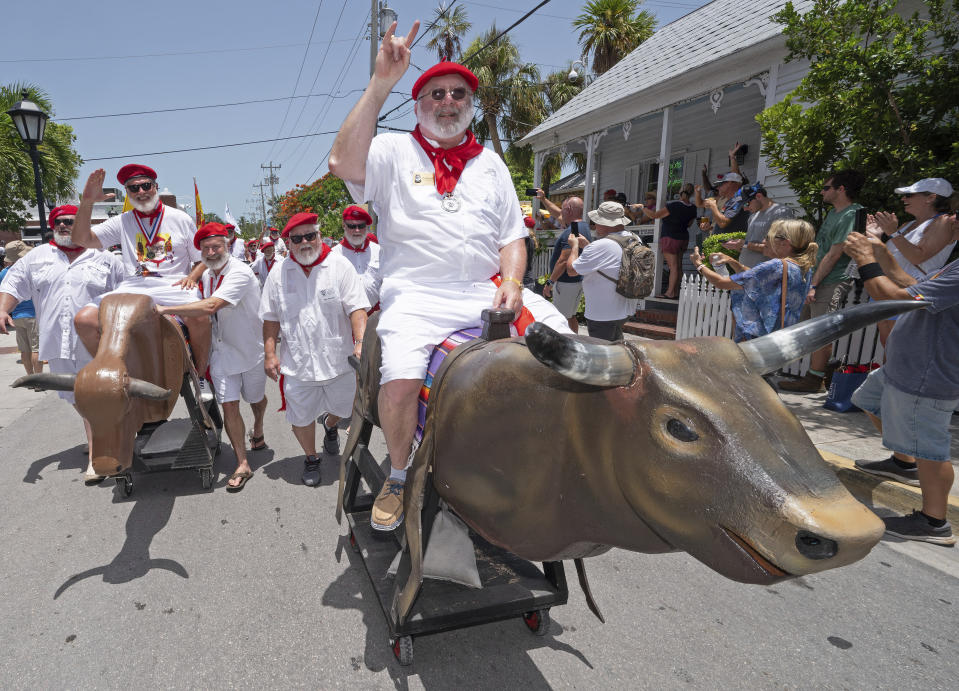 In this photo provided by the Florida Keys News Bureau, Chuck Swaim, right, and other Ernest Hemingway look-alikes ride and push mock bulls during the "Running of the Bulls" Saturday, July 22, 2023, in Key West, Fla. The lighthearted take-off on the famed run in Pamplona, Spain, features replica bulls on wheels and is a focal element of the island city's annual Hemingway Days festival that ends Sunday, July 23. The Nobel Prize–winning author lived and wrote in Key West throughout most of the 1930s. (Andy Newman/Florida Keys News Bureau via AP)