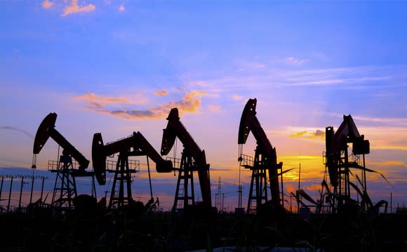 Several oil pumps in a row at dusk.