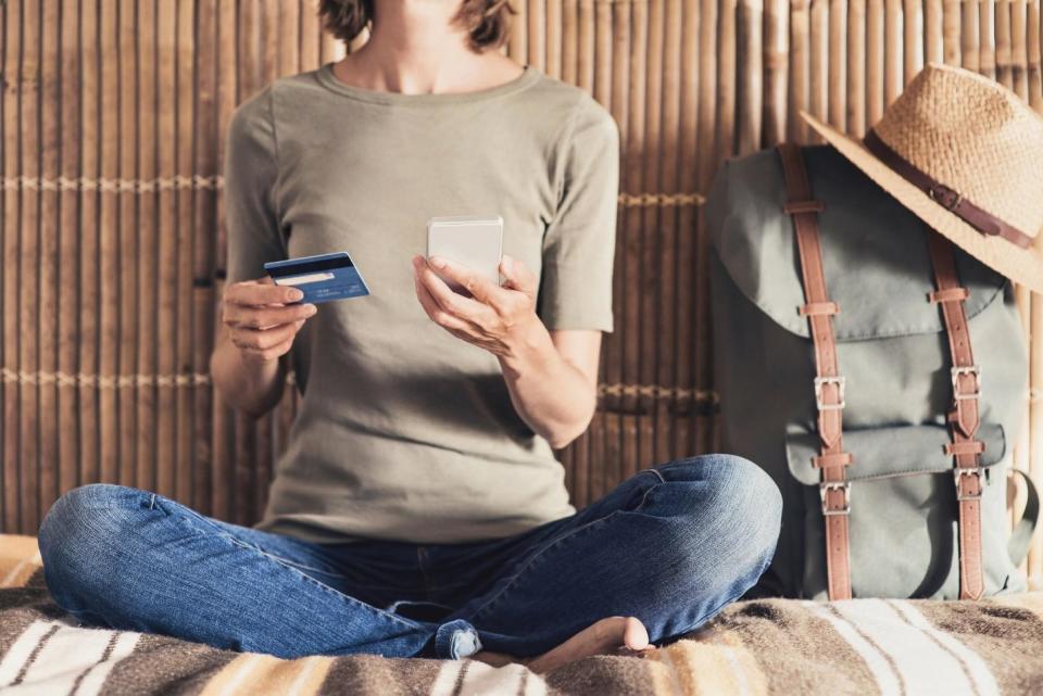 Female Traveler Looking At Cell Phone And Credit Card