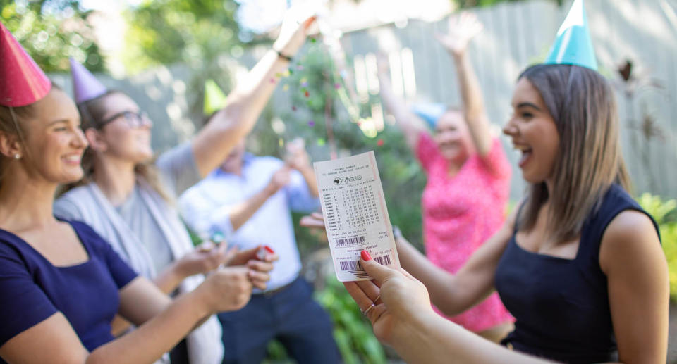 Woman holds up winning tickets as people celebrate. Source: The Lott