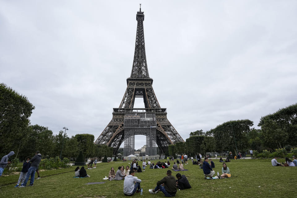 FILE - People relax at the Champ-de-Mars garden in front of the Eiffel Tower in Paris, Friday, July 16, 2021. The Champ-de-Mars will host Beach volleyball and Blind football at the Paris 2024 Olympic and Paralympic Games. (AP Photo/Michel Euler, File)