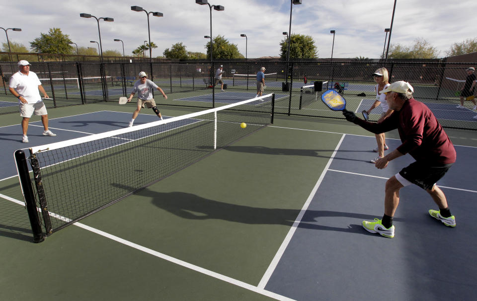 In this Monday, Dec. 3, 2012 photo, clockwise from left; Gary Dyson, Del Teter, Donna Shattenberg and David Bone compete in a game of pickleball at Sun City West senior community in Surprise, Ariz. A hybrid of tennis, badminton and table tennis, pickleball is played on a court a quarter the size of a tennis court, with hard rackets and a variety of whiffle ball. 