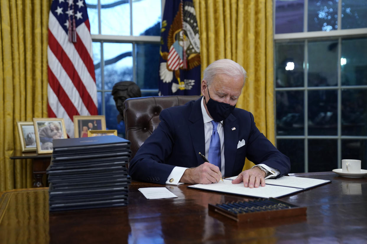 FILE - In this Jan. 20, 2021, file photo, President Joe Biden signs his first executive order in the Oval Office of the White House in Washington. Biden laid out an ambitious agenda for his first 100 days in office, promising swift action on everything from climate change to immigration reform to the coronavirus pandemic. (AP Photo/Evan Vucci, File)