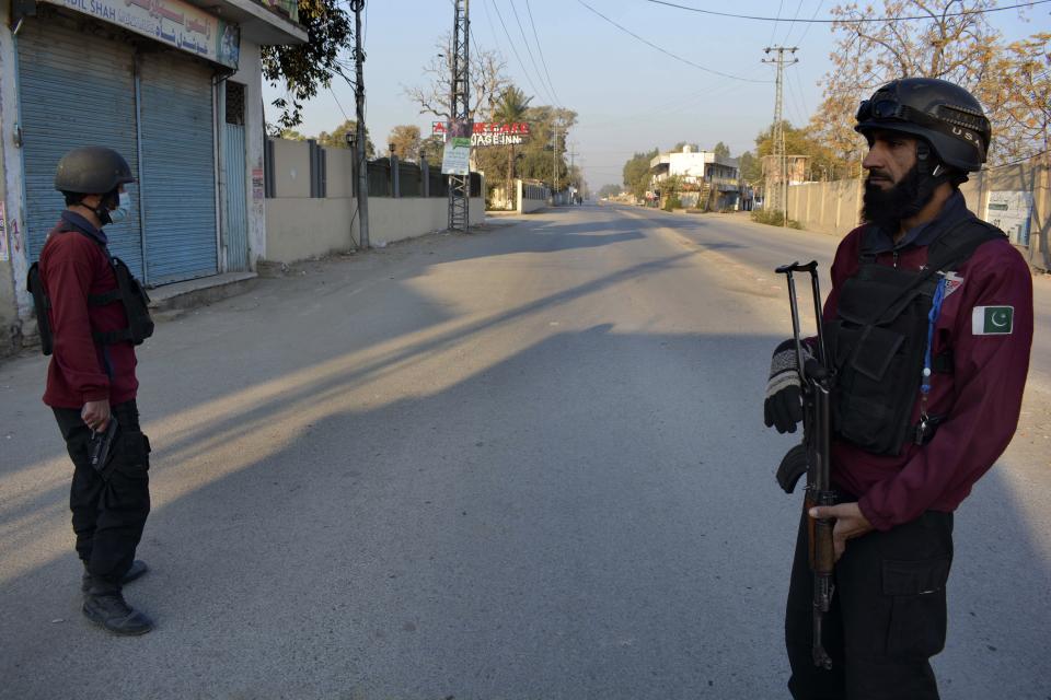 Security officials stand guard on a blocked road leading to a counter-terrorism center where several Pakistani Taliban detainees have taken police officers and others hostage inside the compound, in Bannu, a district in the Pakistan's Khyber Pakhtunkhwa province, Monday, Dec. 19, 2022. Several Pakistani Taliban detainees have managed to overpower their guards at the counter-terrorism center, snatching police weapons and taking control of the facility, officials said Monday. (AP Photo/Muhammad Hasib)