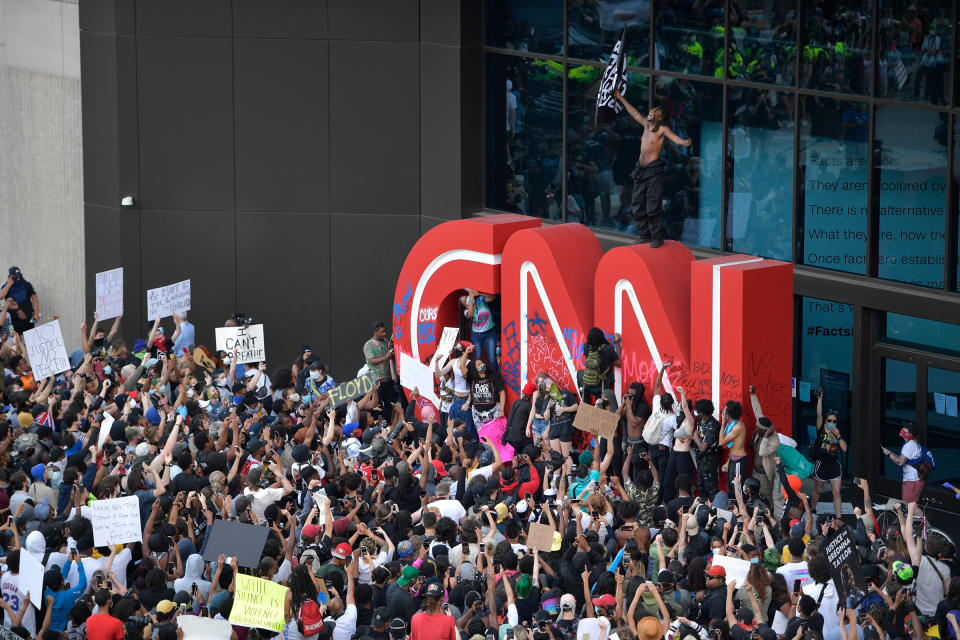 Demonstrators paint on the CNN logo during a protest march in Atlanta, Ga., May 29, 2020. The protest started peacefully earlier in the day before demonstrators clashed with police. | Mike Stewart—AP