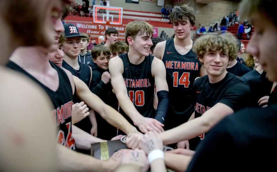 Metamora's Tyler Mason (10) joins some of his teammates and fans as they lay their hands on the Class 3A supersectional plaque after their 60-48 victory over Marmion Academy on Monday, March 6, 2023 at Ottawa High School.