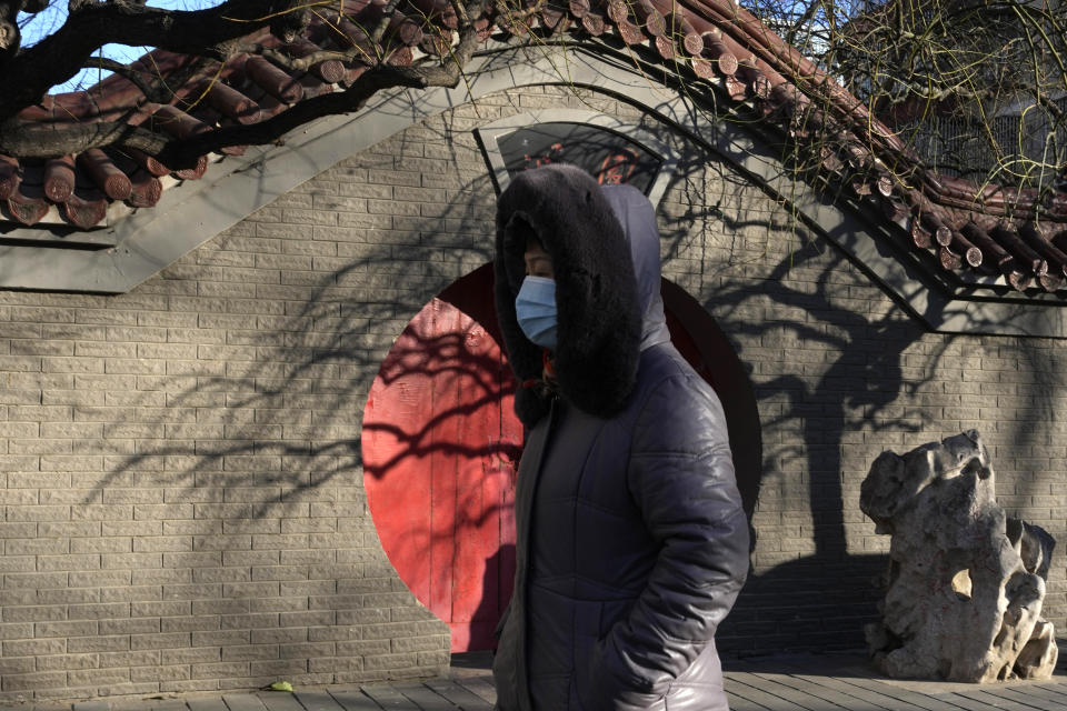 A resident wearing mask past by a traditional entrance way in Beijing, Friday, Dec. 16, 2022. A week after China dramatically eased some of the world's strictest COVID-19 containment measures, uncertainty remained Thursday over the direction of the pandemic in the world's most populous nation. (AP Photo/Ng Han Guan)