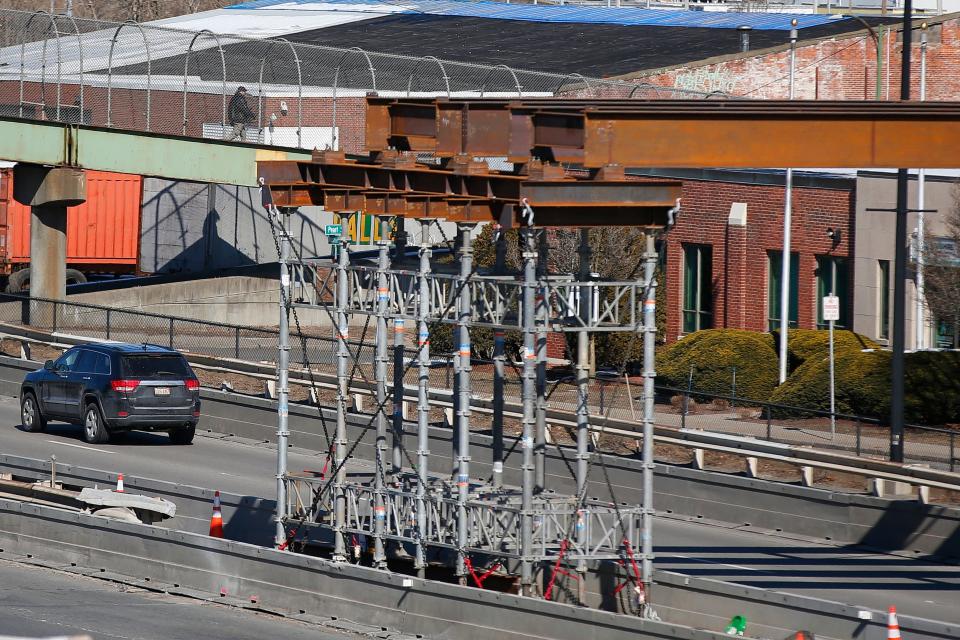 A pedestrian is seen crossing the existing overpass in the distance. In the foreground the first two beams spanning above Route 18 northbound, were laid down for the pedestrian overpass connecting Purchase Street to the Whale Tale commuter rail station in New Bedford.